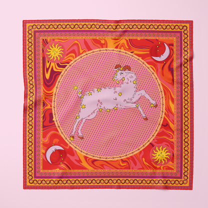 A red and orange silk scarf with sun and moon motifs, a pink and red checkered border, and an Aries ram with constellation on top